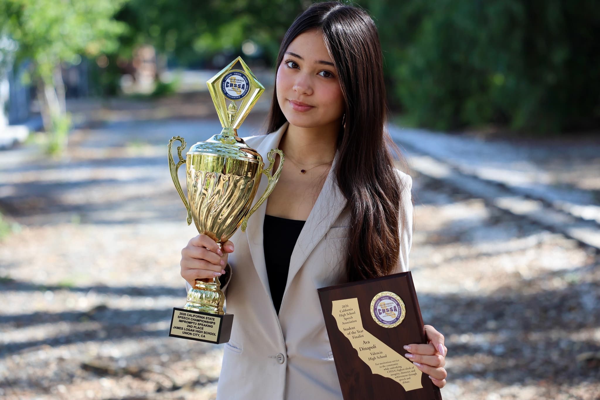 Ava DiNapoli holding her California State speech championship trophy and plaque