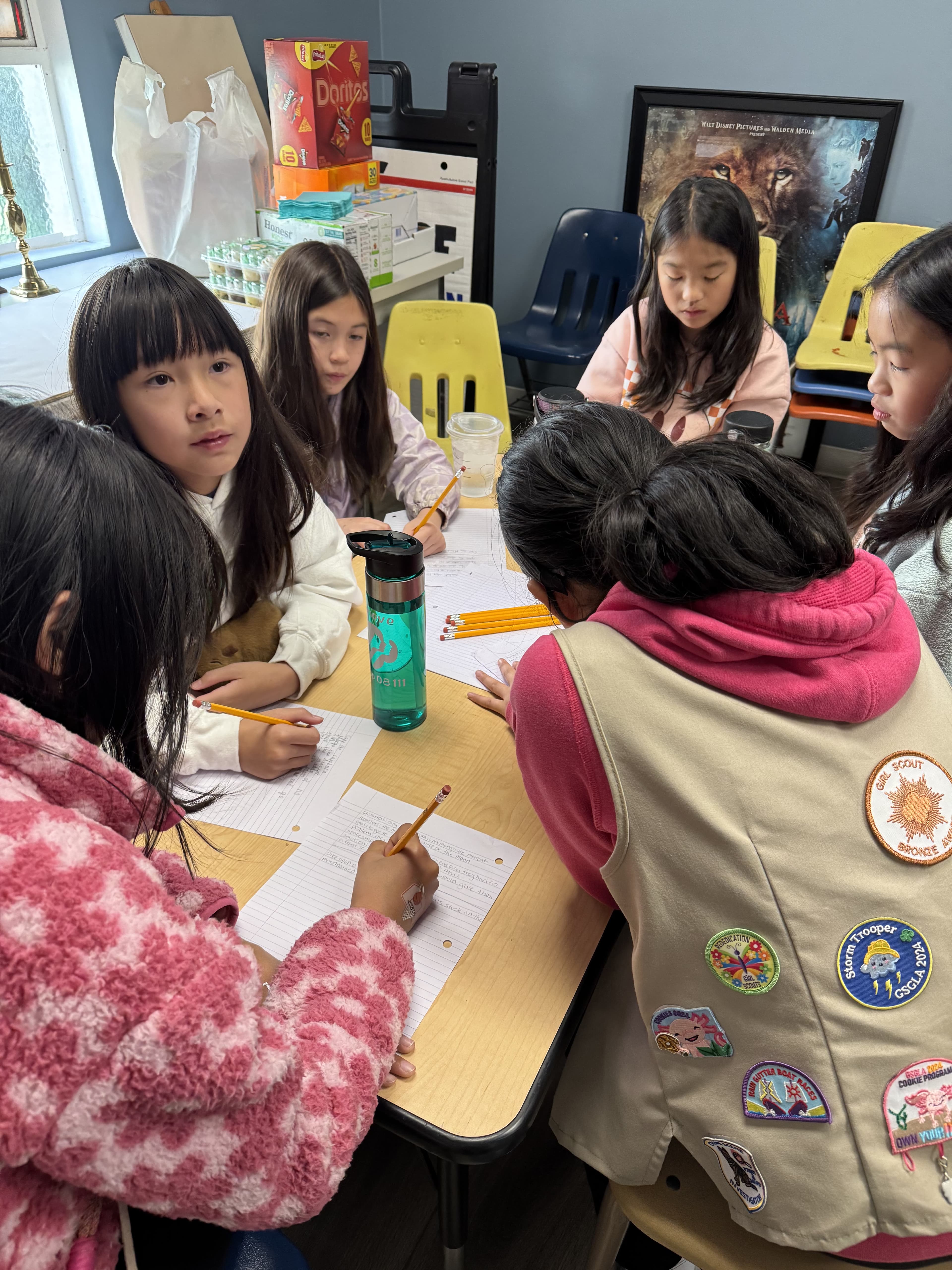 Girl Scouts writing their speeches together at a table